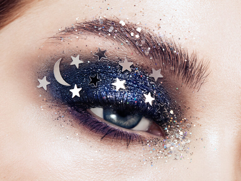 Eye makeup woman with decorative stars. Perfect makeup. Beauty fashion. False Eyelashes. Cosmetic Eyeshadow. Make-up detail. Eyeliner. Creative make-up the night sky with stars