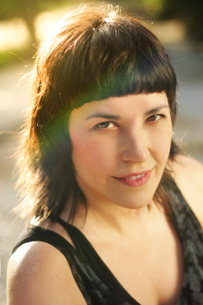 portrait of brunette girl with bangs looking at camera with small smile on outside