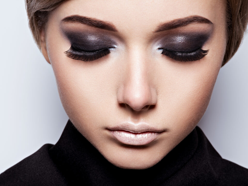 The girl's face closeup with long black lashes. fashion makeup